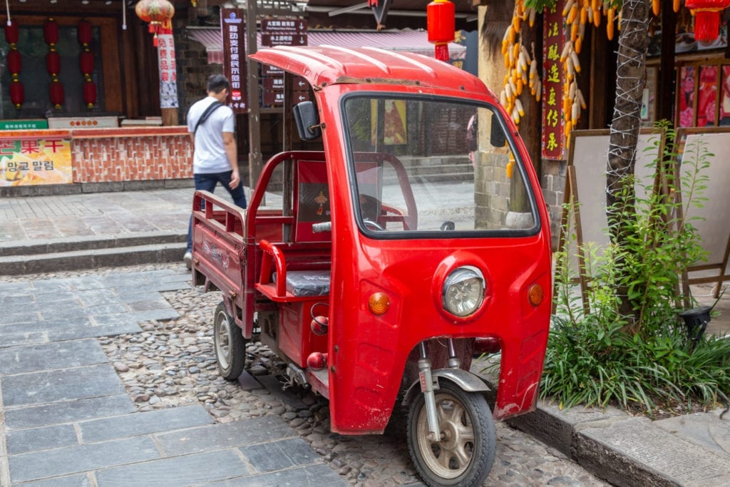 Low-speed electric vehicles found in China transport people and goods through narrow, busy streets.