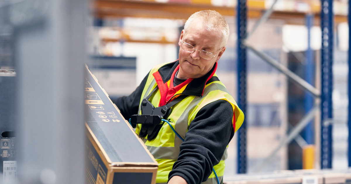 A senior employee wearing an exoskeleton while lifting heavy objects.